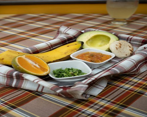 A glass of water and a bowl filled with colorful Colombian local fresh fruits like mango and papaya